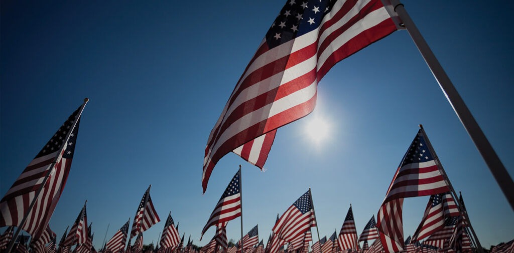 Field of American flags with a blue sky.