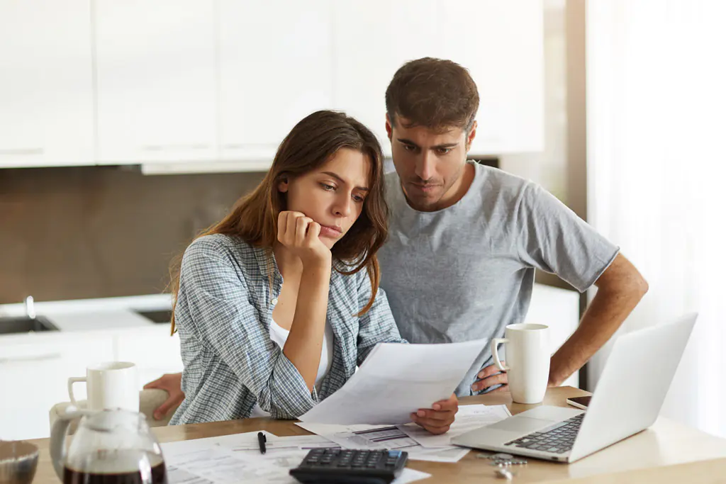 A couple reviews paperwork at a table.
