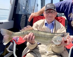 97 year young Gene Wright holding a large fish in both hands while seated.