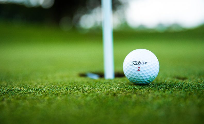 Golf ball near the hole on a green.
