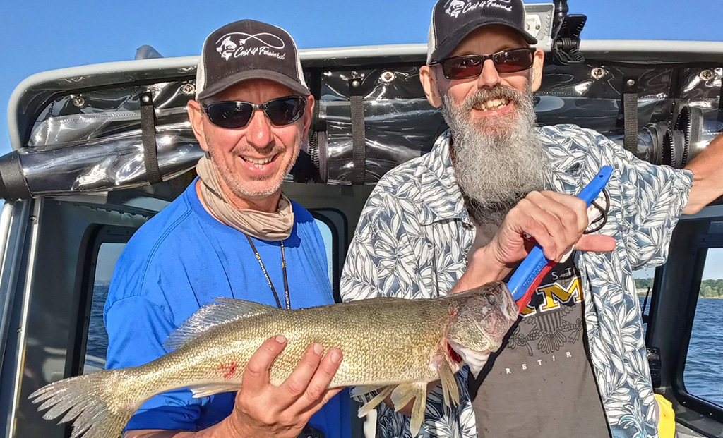 Art Panfil and Bill Holk holding up a fish on a boat.