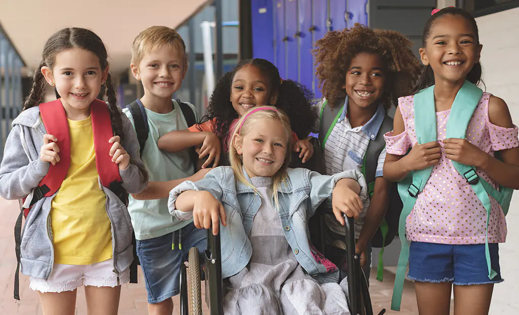 Group of middle school aged kids with backpacks on in the hallway of a school.