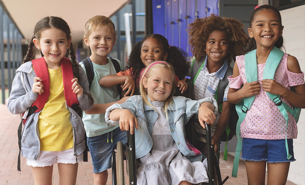 Group of school kids together in a school hallway smiling.