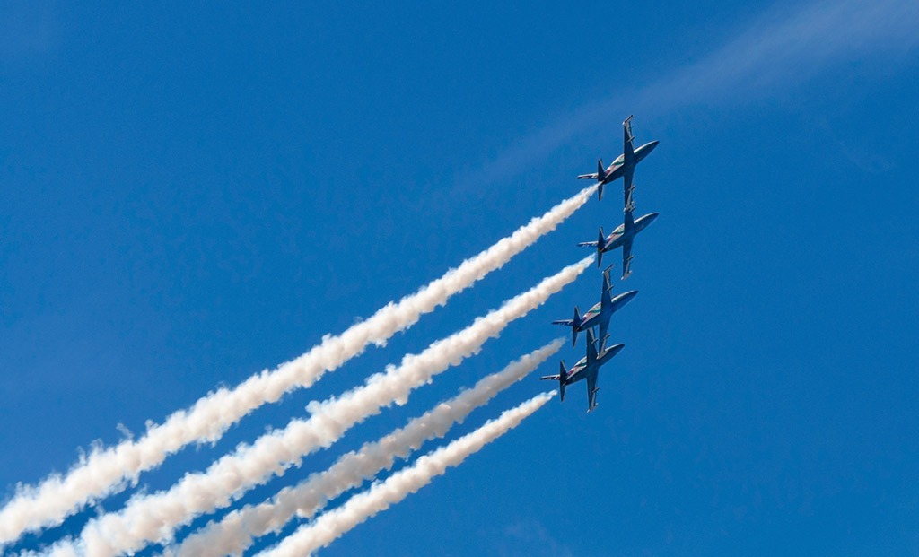 4 planes flying close together with white smoke trails streaming behind.