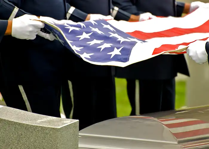 Soldiers holding American flag over a casket.