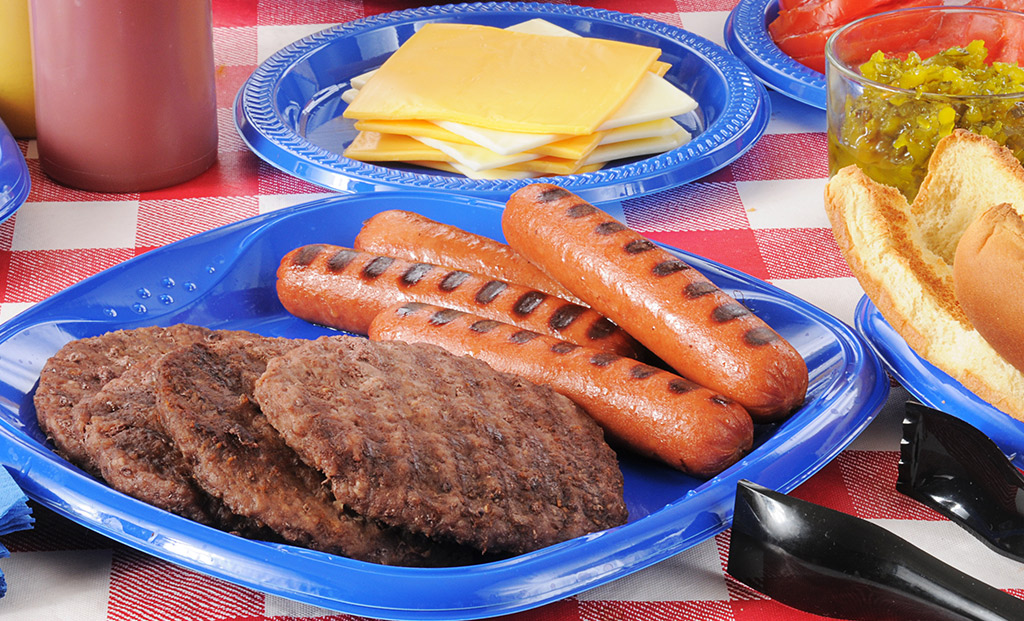 Hot dogs and hamburgers on a blue plate fresh off the grill.