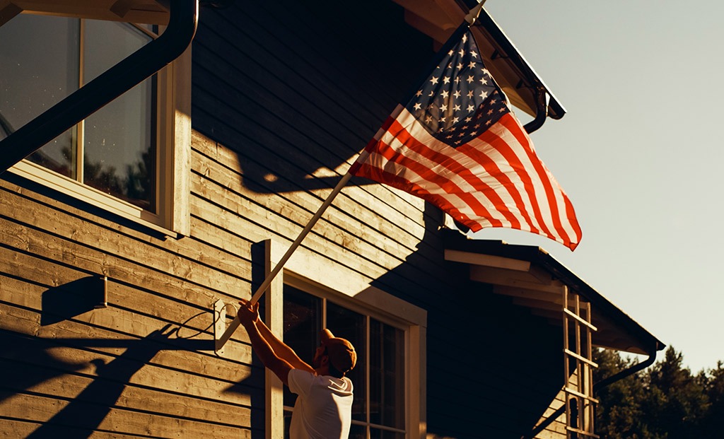 Man taking down his American flag mounted to his house.
